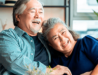 Casal de idosos sentados juntos e felizes. Programa de Assistência ao Idoso oferece atendimento integral aos idosos com equipes formadas por geriatras, fisioterapeutas, nutricionistas, assistentes sociais, terapeutas ocupacionais e fonoaudiólogos.