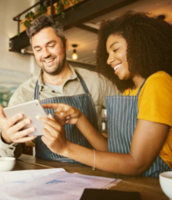 Casal segurando e olhando para o tablet e sorrindo