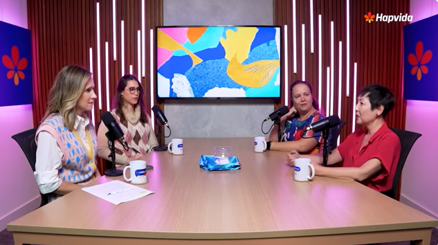 Quatro pessoas conversando na mesa do podcast.