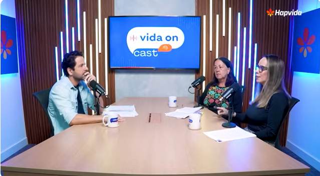 Três pessoas conversando na mesa do podcast.